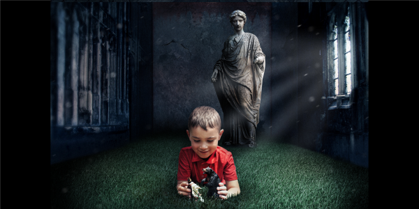 Young boy plays with a toy, watched over by a female statue