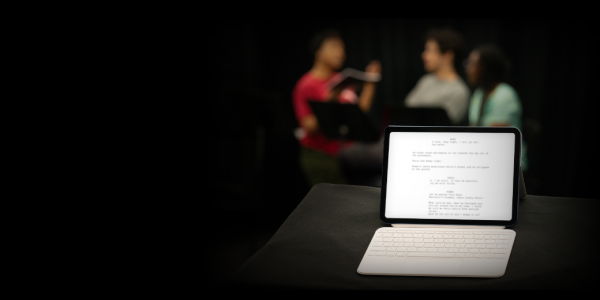 iPad with a blurred play script and three figures blurred in background