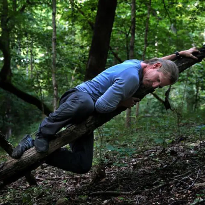 David Marchant, a professor of practice, tests his balance on a small tree limb at Tyson Research Center.