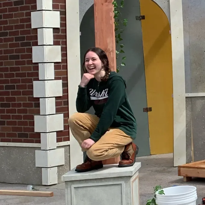 Katie Plum poses with statues on Shakespeare set